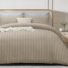 Beige striped bedding set on a bed with pillows and a nightstand in the background.