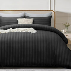 Black striped bedding set on a bed with pillows and a nightstand in a bedroom.
