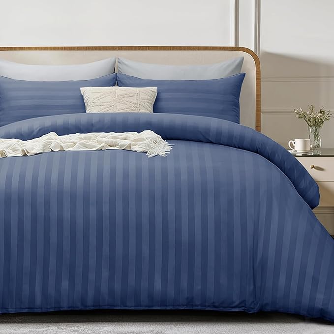 Blue striped bedding set on a bed with pillows and a nightstand.