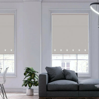 Modern interior featuring light grey square eyelet roller blinds filtering sunlight through large windows.