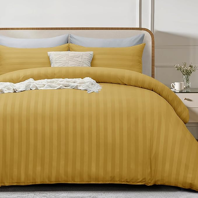 Yellow striped bedding set on a bed with a white nightstand in the background.