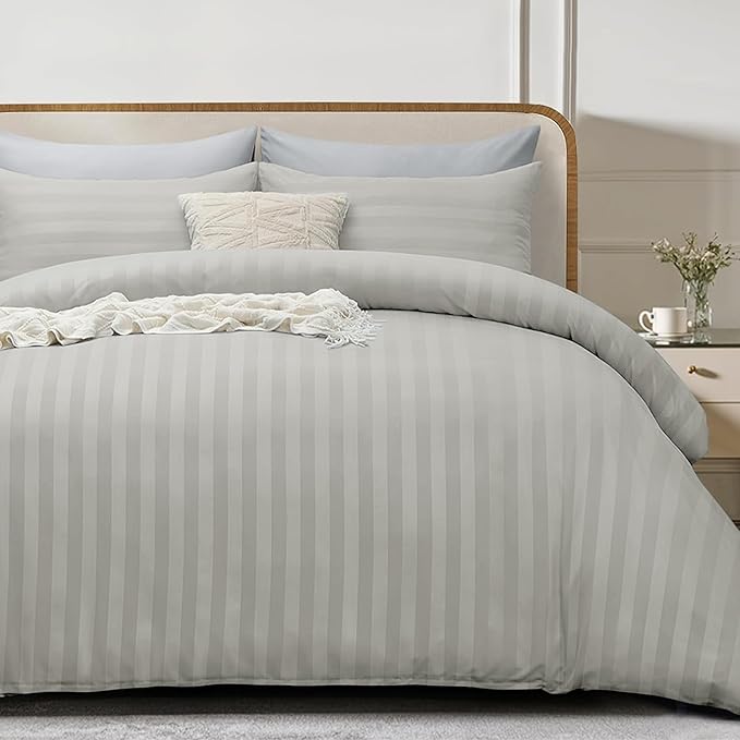 silver striped bedding set on a bed with a wooden headboard.
